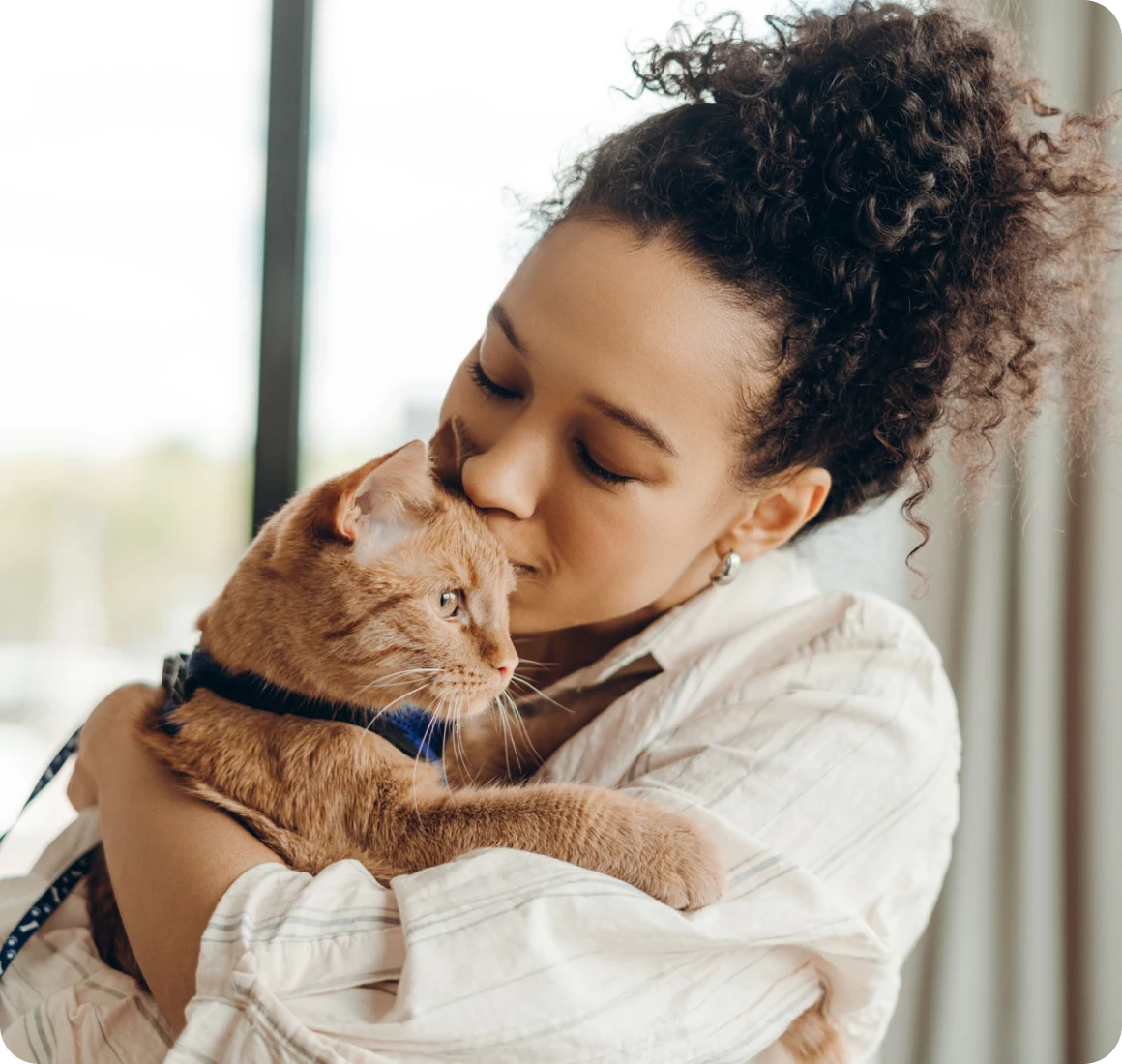 Woman lovingly holding an orange cat.