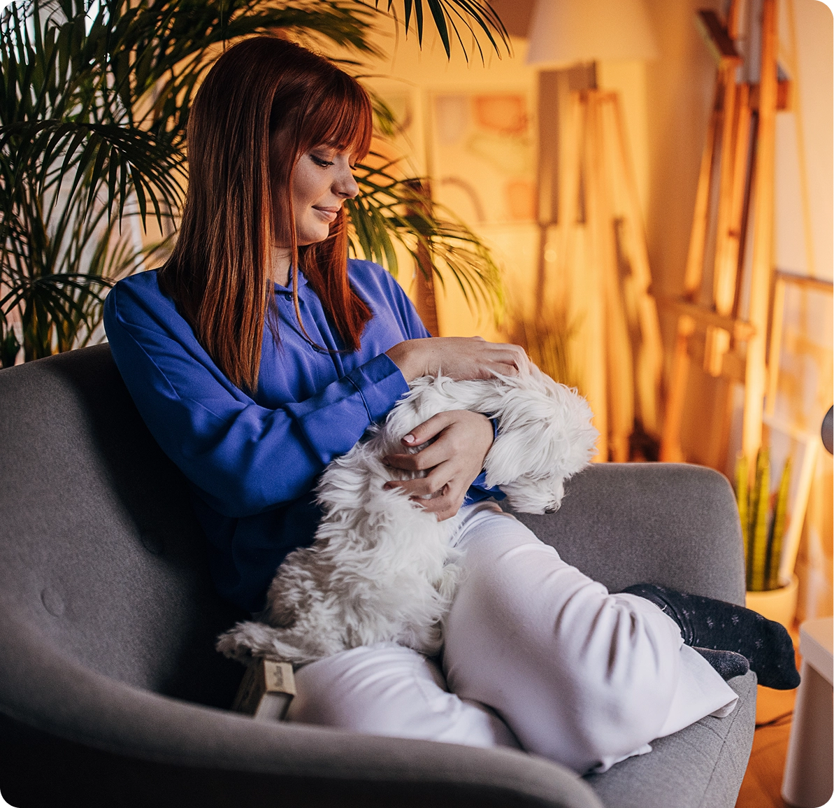 Woman cuddling a dog on a chair.